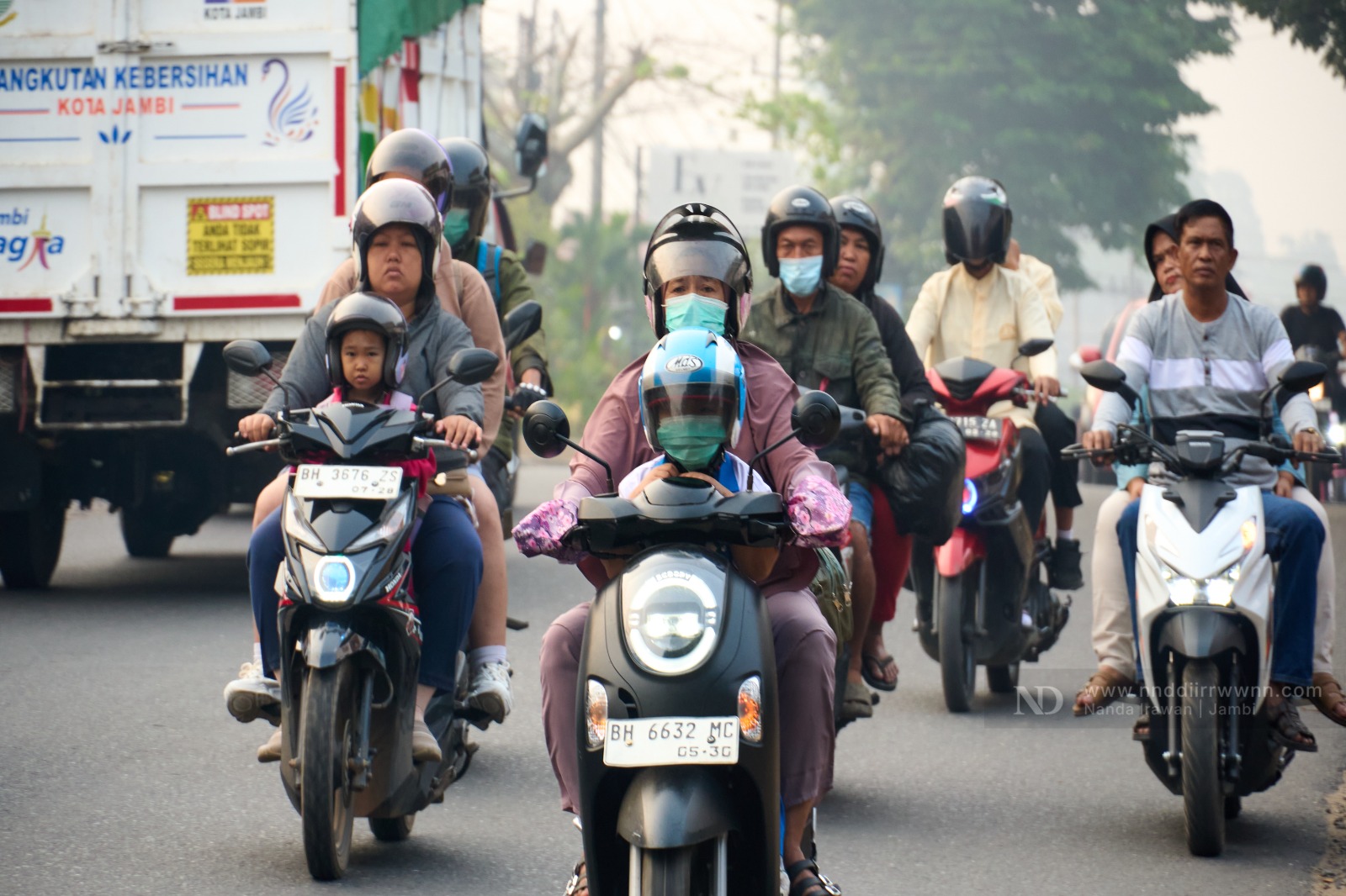Sejumlah pengendara motor dan anak sekolah menggunakan masker saat menembus kabut asap di jalan protokol Kota Jambi, Senin (24/8/2026). Pemkot Jambi mengimbau warga memakai masker akibat memburuknya kualitas udara akibat Karhutla. Foto: Nanda Irawan